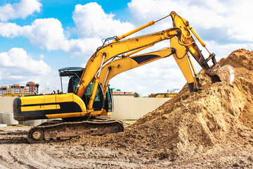 Two powerful excavators work at the same time on a construction site, sunny blue sky in the background. Construction equipment for earthworks.
