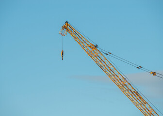 Bright yellow Industrial construction crane against a blue sky