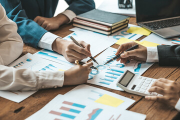 A desk in a company conference room has a group of business people attending and with supporting documents laid out, brainstorming sessions to fix and plan the company's growth. Business meeting idea.