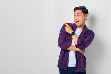 Shocked young Asian man in plaid shirt pointing fingers at copy space, advertisement banner isolated on white background