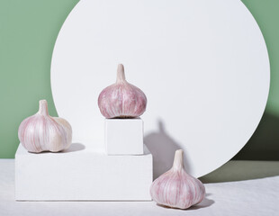 The whole unpeeled garlic on white geometric podium or pedestal. raw garlic, cooking and spice concept. trendy food shot.