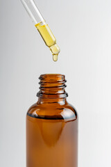 Dripping natural tea tree essential oil into bottle on white background. Skin care treatment. Acne...