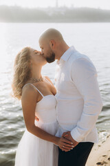 Wedding photosession at sunset of a beautiful couple, the bride in a white dress, and the groom in a white shirt and black trousers