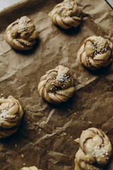 laid out raw cinnamon buns on baking paper top view. ready-to-bake cinnamon buns on a baking sheet. bake cinnamon rolls garnished with white sugar.