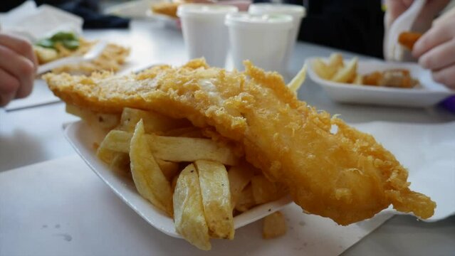 Family and friends eating fish and chips in a traditional English cafe chip shop