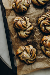 freshly baked cinnamon buns on baking paper top view. baked cinnamon buns on a baking sheet. cinnamon buns topped with white granulated sugar.