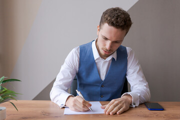 Businessman, executive manager manually fills paper business document, contract signing, partnership agreement and work on desk in modern office, closeup. Caucasian bearded guy