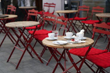 Empty tables of street cafe leftover food (cherry pie and coffee), Cafe Terrace in old town, patio chair and table in cafe restauran