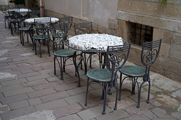 Fototapeta na wymiar Empty tables of street cafe during lockdown, coronavirus quarantine, Cafe Terrace in old town, outdoor patio chair and table in cafe restaurant