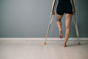 Disabled woman walking with crutches and sprained ankle