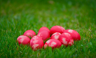 Red painted Easter eggs on green grass. Beautiful orthodox and catholic Easter decorations.