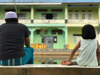 Fototapeta premium Father and son taking fishing line with hook and lure out of water