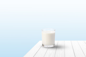 Glass of fresh milk on white wooden table with blue background. Copy space.