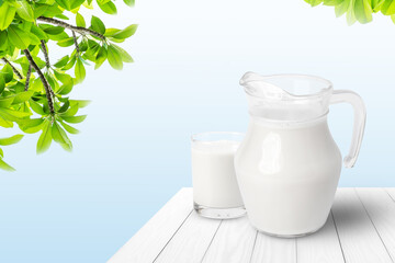 Jug and glass of fresh milk on white wooden table with blue background. Copy space.