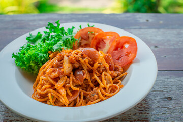 Spaghetti with ketchup on wooden floor ready to serve.
