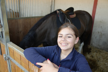 young girl preparing her horse in a stable