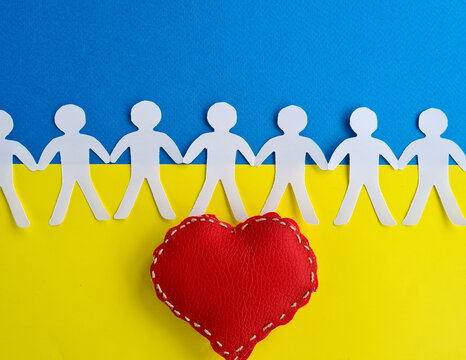 Figures of paper people hold hands against background of Ukrainian flag and red heart