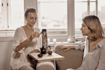Two women are drinking tea while conducting a Chinese tea ceremony and talking.
