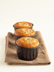 Banana cupcakes in the brown paper baking forms on beige linen cloth, high key, close up