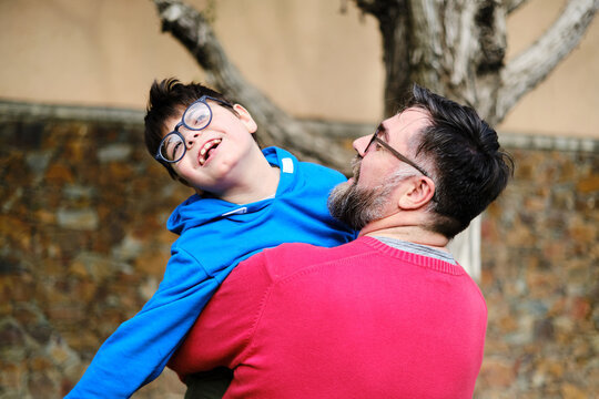 Loving father holding and playing with his disabled son while enjoying time together outdoors.