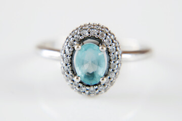 beautiful ring with blue topaz and many white diamonds on white background, closeup