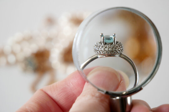 jeweler looking at ring with blue stone, jewerly inspect and verify, pawnshop concept, jewerly shop