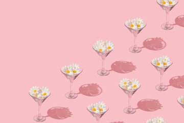Spring creative pattern with martini cocktail glasses and white flower heads  on pastel pink...