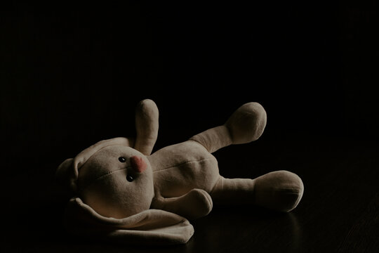 Plush bunny laying down alone in the dark. Lonely concept, international missing children's day - Powered by Adobe
