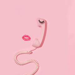 Valentines day creative layout with pink retro phone handset, false eyelash and kiss print on...