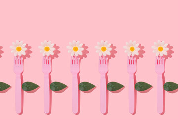 Spring creative pattern with pastel pink fork, white flower heads and leaves on pastel pink...