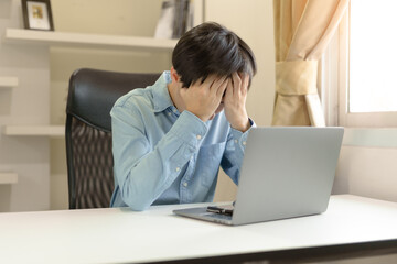 Stressed young businessman, trader or investor touch head, disappointed when bad investment or economic crisis, losing money from investing, trading stock, Cryptocurrency as Bitcoin on laptop at home.