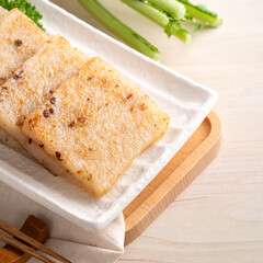 Delicious Chinese radish cake in a plate on wooden table background.