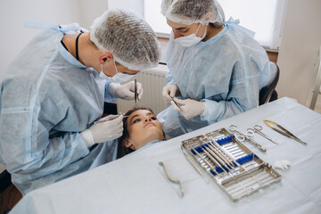 Obraz premium Team of surgeon in uniform perform operation on a patient at plastic surgery clinic