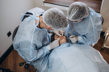 Team of surgeon in uniform perform operation on a patient at plastic surgery clinic