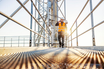 A heavy industry worker walking and talking on the phone on height.