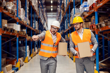 Two inspectors carry boxes with goods and relocating it.