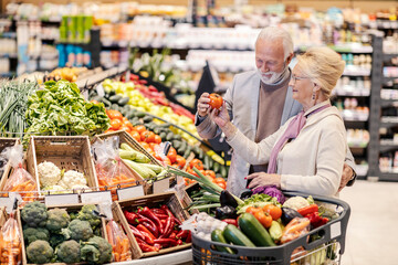 A senior couple purchasing vegetables at supermarket.