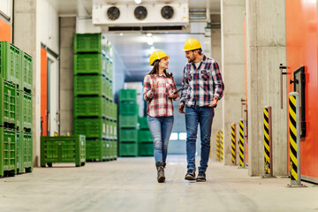 A manager with tablet talking to factory worker and giving orders while walking around facility.