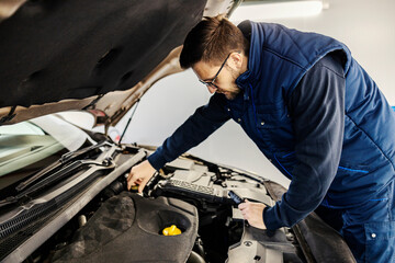 Fototapeta na wymiar A mechanic fixing car engine under the hood at workshop.