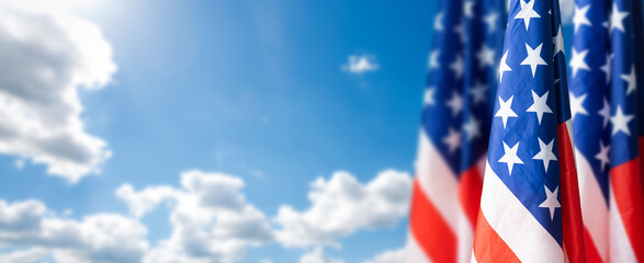 Large flag of usa waving in the wind against the sky with clouds on sunny day.