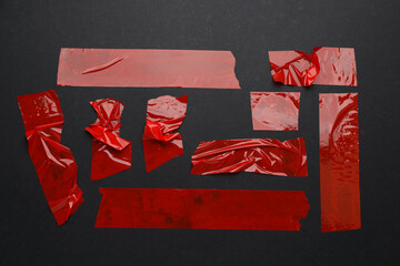 Many pieces of red adhesive tape on black background, flat lay