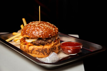 Fast food hamburger and french fries on a metal plate