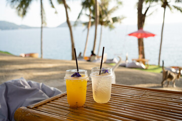 Fresh cups orange juice drink water summer on table seaside during sunset sky.