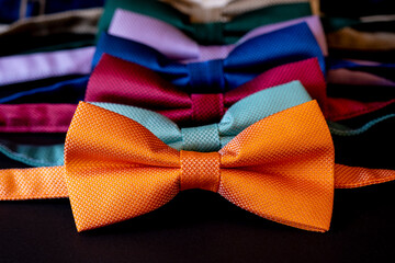 Colorful bow ties arranged in a row, orange color necktie on the front, selective focus, close-up