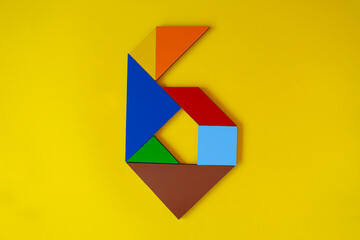 Colorful number 6 made with tangram toy, colored tangram number six isolated on yellow background, kids game idea, teaching counting for children, puzzle toy, top view of sixth numeric