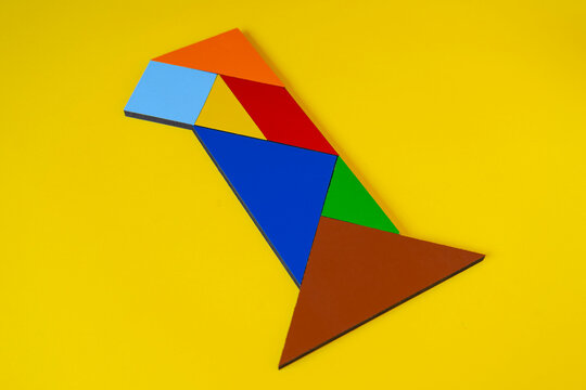 Colorful number 1 made with tangram toy, colored tangram number one isolated on yellow background, kids game idea, teaching counting for children, puzzle toy, side view of first numeric