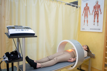 Magnet therapy system. Patient on a treatment bed with Magnetic Field Therapy on her leg. Medicine concept