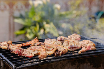 Man cooking pork chops on barbecue grill for an outdoor summer party. Smoke from the barbecue. Background of food.