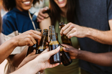 Multiracial young friends cheering with beer at summer music party