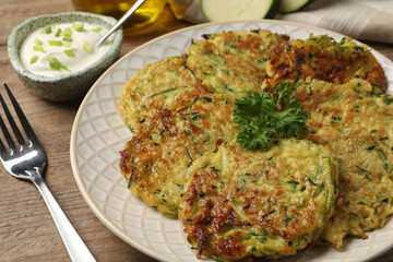 Delicious zucchini fritters served on wooden table, closeup